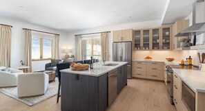 A modern kitchen with a central island, built-in appliances, and light wood cabinetry. - 5BR Ski-In Condo in Okemo Mountain | Near Lifts! (Ludlow)
