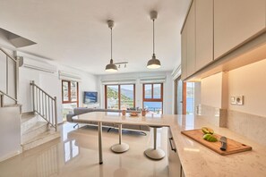 A modern kitchen with a central island, stainless steel appliances, and a view of the sea. - Villa Elmas in Kalkan (Kalkan Belediyesi)