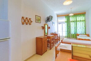 A room with a bed, a desk, a chair, a wardrobe, and a television. - Faros Dio: Gaios studio, sea views, private sun-loungers (Gaios)