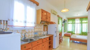 Eine kleine Küche mit Holzschränken, einem Kühlschrank und einem Essbereich mit Tisch und Stühlen.