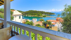 Un balcone con vista su una cittadina costiera, tra case e uno specchio d'acqua.