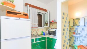 Una cucina compatta con mobili verdi, un frigorifero bianco e un forno a microonde.
