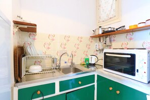 A kitchen with green cabinets, a sink, a dish rack, a microwave, and a shelf with kitchen utensils. - Faros Pende in Gaios (Gaios)