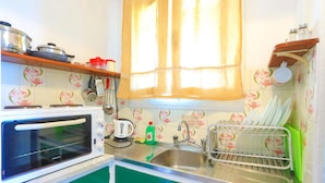 Eine Küche mit Mikrowelle, Wasserkocher, Spüle und Geschirrgestell.