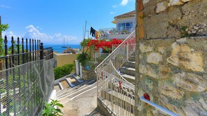 Una scala in pietra conduce a un balcone con vista sul mare.