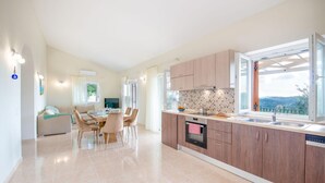 Una cocina moderna con armarios de madera, un comedor con sillas y un amplio ventanal con vistas.