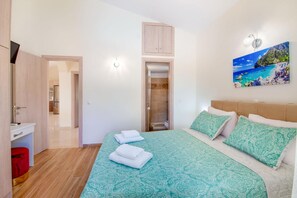 Een slaapkamer met een bed, een schilderij, een kledingkast, een badkamer en een gang.