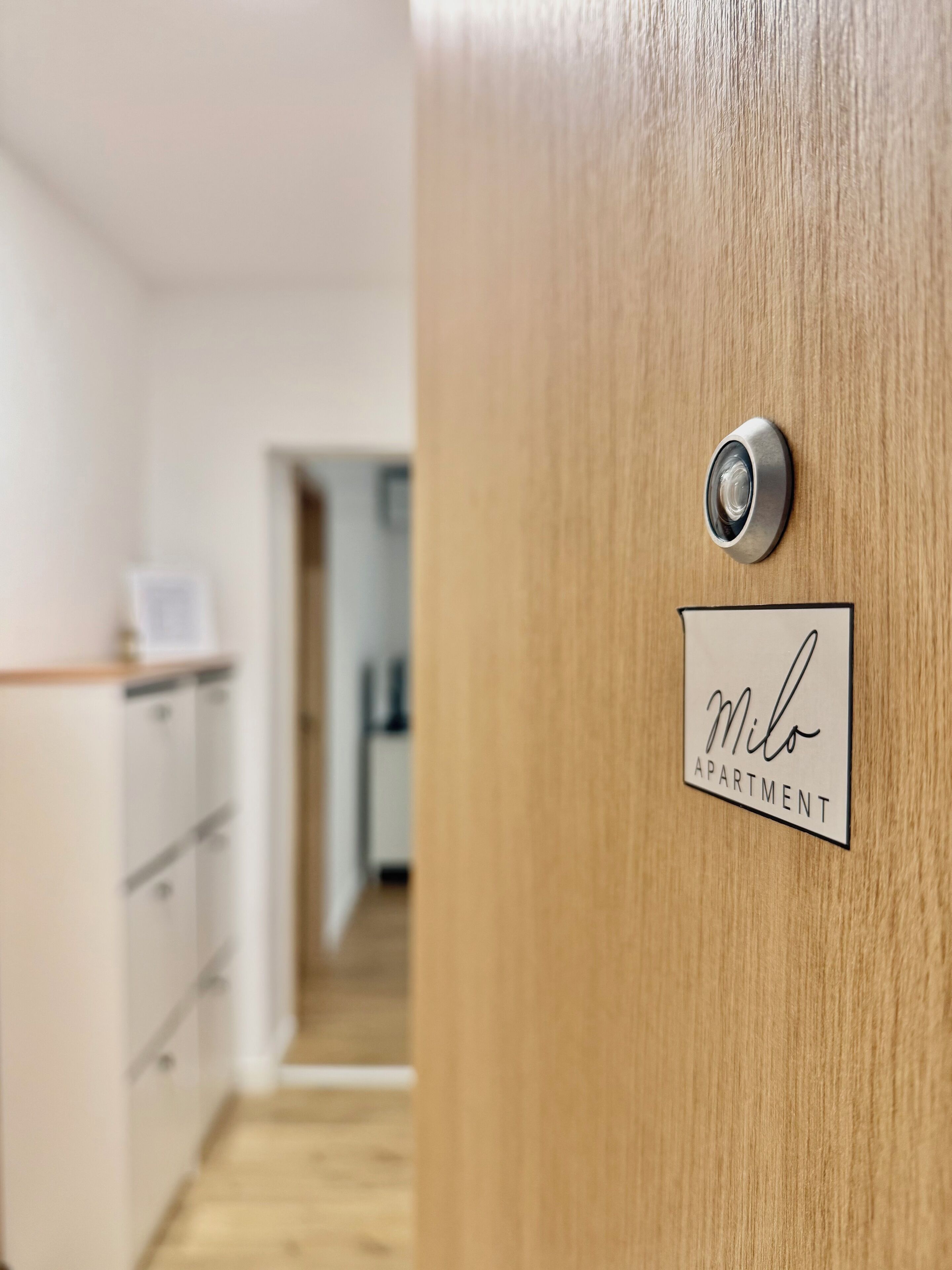 Une porte en bois, dotée d’une serrure et d’une plaque indiquant « Appartement Milo ».