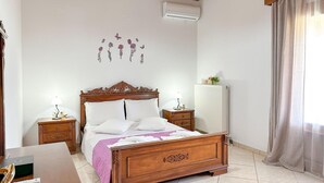 Une chambre à coucher avec un lit en bois, deux tables de chevet avec des lampes, un radiateur et une décoration murale représentant des fleurs et des papillons.