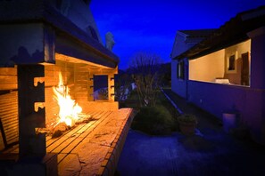 A courtyard with a fire feature, a brick wall, and a window with a view of the sky. - Villa Limoncello in Agrafi (Agrafi)