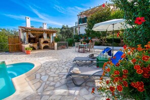 A stone patio with a pool, outdoor seating, and a barbecue area. - Villa Yiotta in Paxi (Paxi)