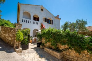 A white building with arched windows and a stone wall. - Villa Eleni Paxos in Gaios (Gaios)