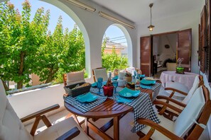 An outdoor dining area with a round table, chairs, and a view of trees and buildings. - Villa Eleni Paxos in Gaios (Gaios)