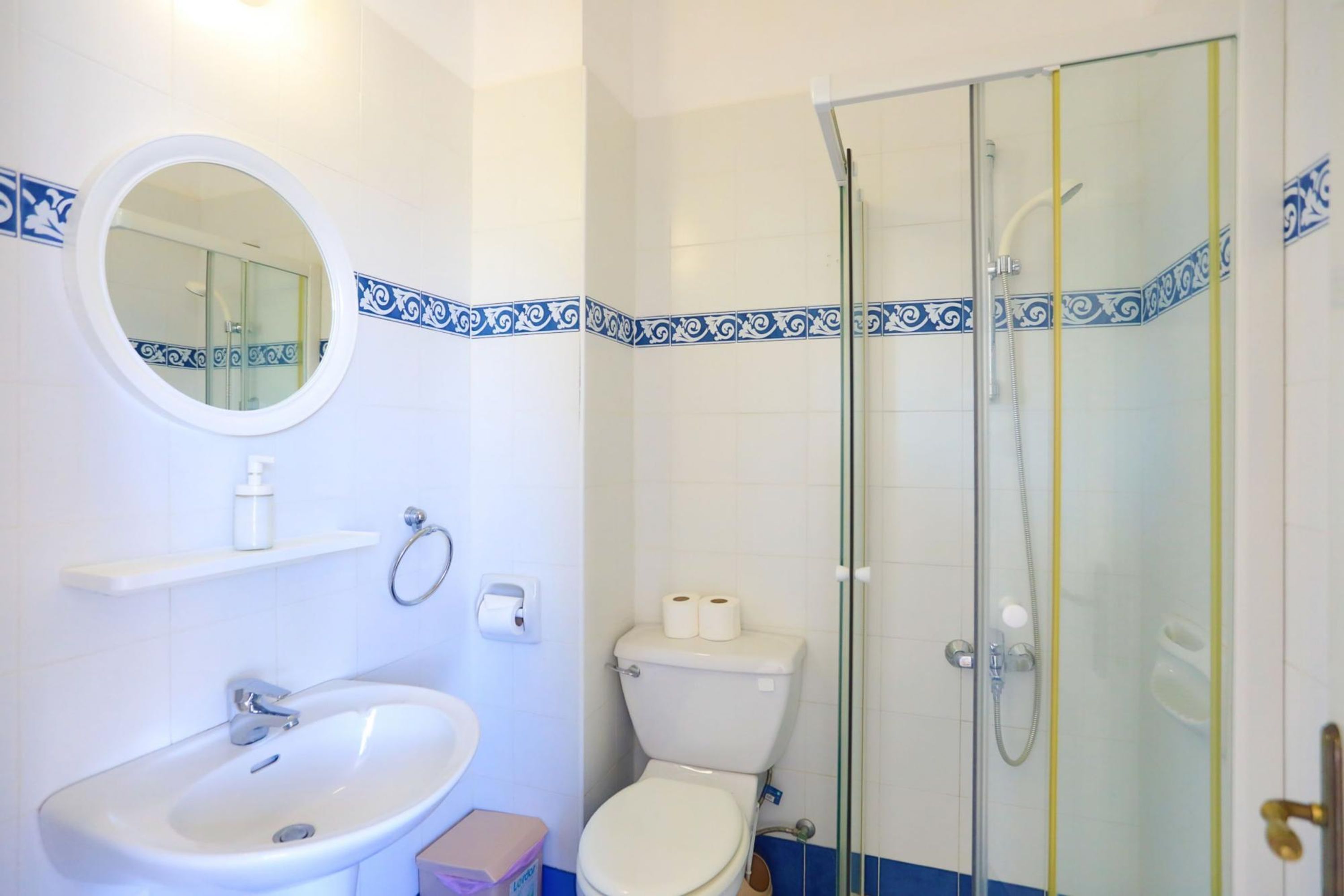 A bathroom with a white sink, toilet, and glass-enclosed shower.