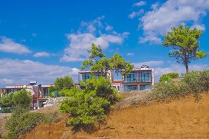 A modern two-story building with large windows and a flat roof, surrounded by trees and a hilly landscape. - Kalma Villa Ena in Moudania (Moudania)