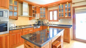 A kitchen with wooden cabinets, a granite countertop, and stainless steel appliances. - Villa Eos in Kalkan with 3 bedrooms and 4 bathrooms (Kalkan)