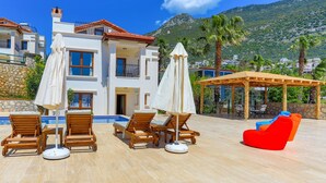 A modern villa with a pool, outdoor seating, and a mountain backdrop. - Villa Eos in Kalkan with 3 bedrooms and 4 bathrooms (Kalkan)