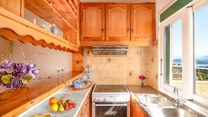 Una cocina con armarios de madera, estufa, lavavajillas y ventana con vistas.
