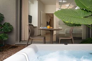 A hot tub with a table and chairs outside a room. - Athens Hill - Garden Apartment with Hot Tub (Kallithea)