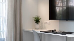 A modern office space with a white desk, a potted plant, and a mounted TV. - Athens Hill - Superior Apartment with Balcony (Kallithea)