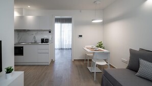 A modern, minimalist living space with a kitchen, dining area, and a sofa. - Athens Hill - Superior Apartment with Balcony (Kallithea)
