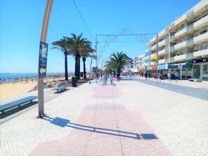 A beach promenade with palm trees, benches, and a clear view of the sea. - T0 A/C Varandas Mar 3ºB perto PRAIA Wi-Fi (Quarteira)