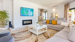 A modern living room with a sofa, a coffee table, and a TV mounted on the wall. - Casinha in Albufeira (Albufeira)