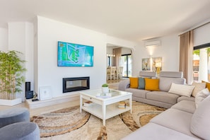 Ein modernes Wohnzimmer mit einer Couch, einem Couchtisch und einem an der Wand befestigten Fernseher.