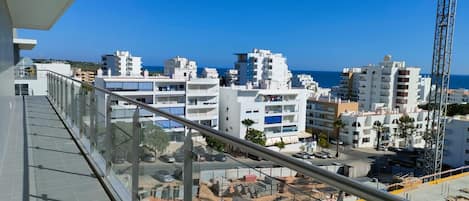 A balcony with a view of a coastal cityscape, including buildings and a construction site.