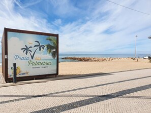 A beachside sign with palm trees and the text "Praia das Palmeiras" indicating a beach location. - T3 Alto Forte -Vista Mar,Ar Condicionado,Garagem (Quarteira)