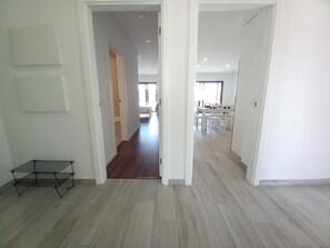 A spacious hallway with a dining area in the background, featuring a white dining set and chairs. - T3 Alto Forte -Vista Mar,Ar Condicionado,Garagem (Quarteira)