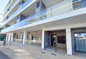 A modern building with multiple balconies, large windows, and a ground-level entrance. - T3 Alto Forte -Vista Mar,Ar Condicionado,Garagem (Quarteira)