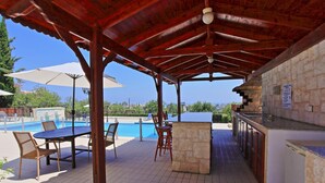 An outdoor pool area with a covered seating area, a bar, and a view of the landscape. - Villa Mandola Rosa in Poli Crysochous (Poli Crysochous)