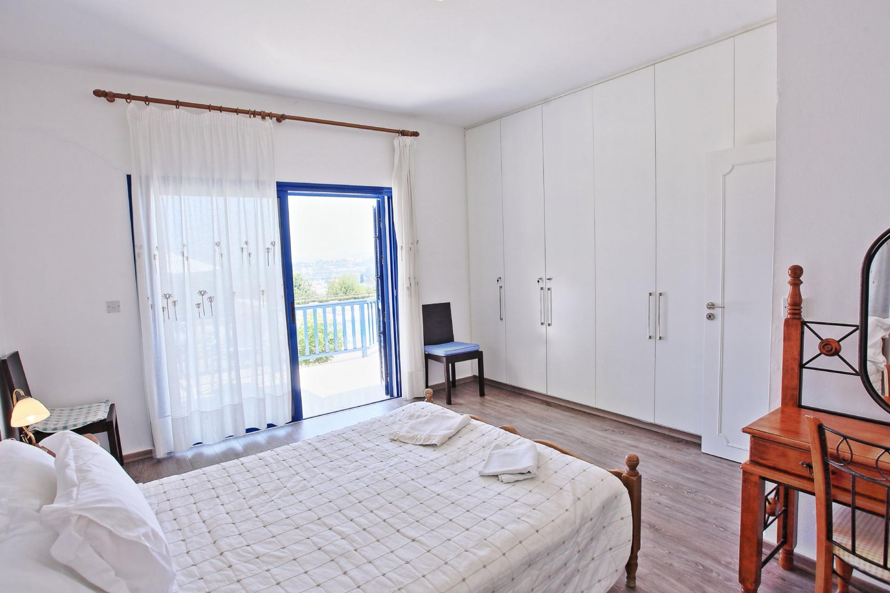 A bedroom with a bed, a chair, a desk, and a wardrobe.