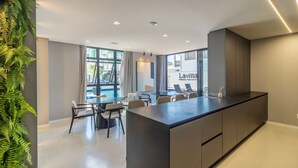 A modern hotel room with a large island, dining area, and a view of the pool. - Condominium w/ Pool, 450 m fr/ the sea and 650 m fr/ Beto Carrero World - Lavs (Penha)