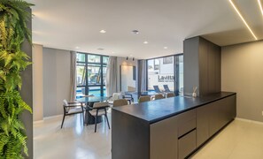 A modern hotel room with a large island, dining area, and a view of the pool. - Condominium w/ Pool, 450 m fr/ the sea and 650 m fr/ Beto Carrero World - Lavs (Penha)