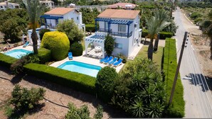 A large house with a swimming pool, blue lounge chairs, and a well-maintained garden. - Lemon Grove Villa Ena (Argaka)