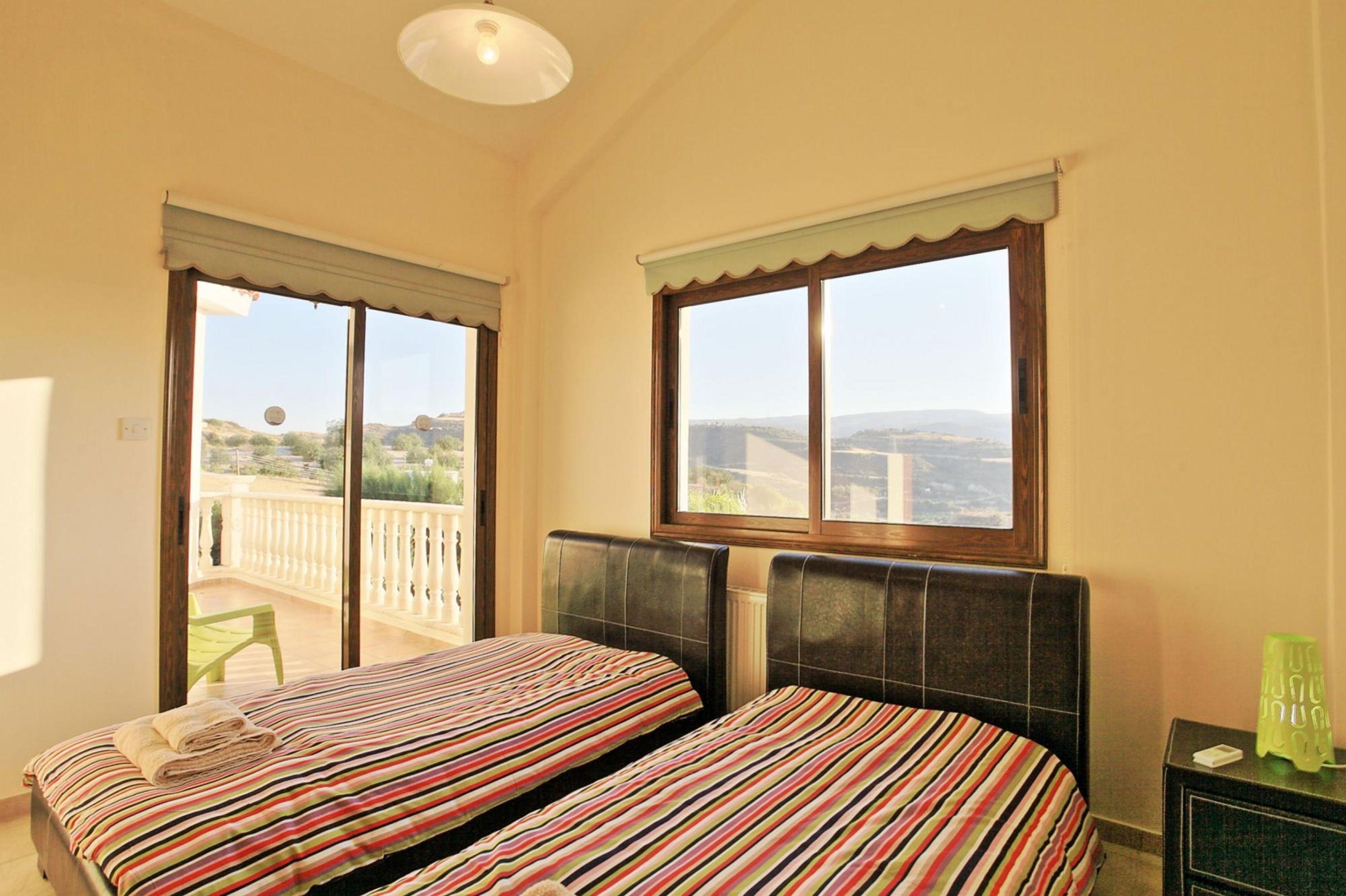 A bedroom with two beds, a balcony, and a view of the landscape.