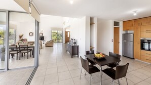 Eine moderne Küche mit Essbereich, großen Fenstern und Blick ins Freie.