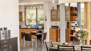 Eine moderne Küche mit Essbereich, Holzschränken und einem Fenster mit Blick auf Grünflächen.
