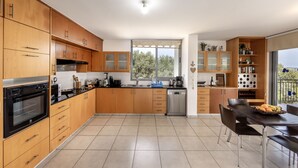 Eine moderne Küche mit Holzausstattung, einem schwarzen Backofen und einem Essbereich mit Tisch und Stühlen.