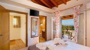 Una camera d'albergo con un letto, televisione, bagno e balcone con tavolo e sedie.