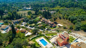 Una vista aerea di una zona residenziale con case, una piscina e vegetazione circostante.