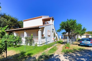 A two-story house with a balcony, a car parked in front, and a clear blue sky. - Beach Villa Vasso Dio (Acharavi)