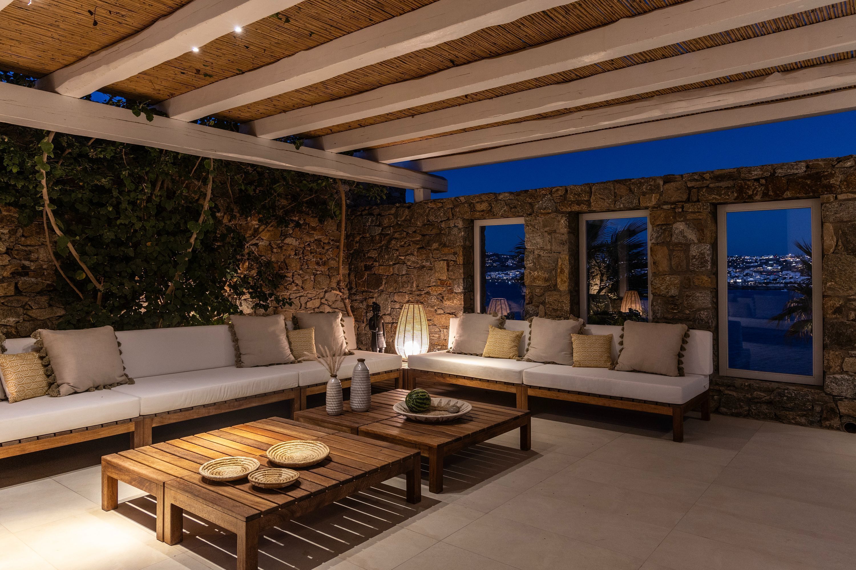 Un espacio exterior acogedor con paredes de piedra y vigas de madera, con un sofá y una mesa de centro.