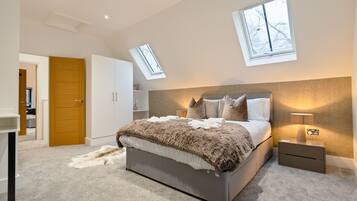 A bedroom with a large bed, a nightstand, a lamp, a wardrobe, and a skylight.