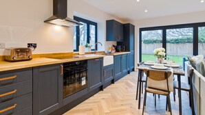 Een moderne keuken met donkere kastjes, een houten aanrechtblad en een eethoek met tafel en stoelen.