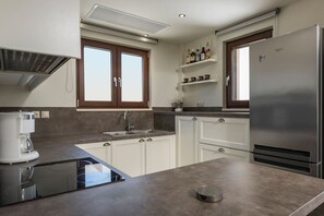 Eine moderne Küche mit weißen Schränken, einem Edelstahl-Kühlschrank, einer Kaffeemaschine und einem Einbauofen.