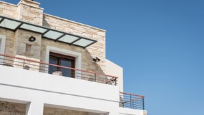 A modern building with stone facade, a glass balcony, and a clear blue sky.