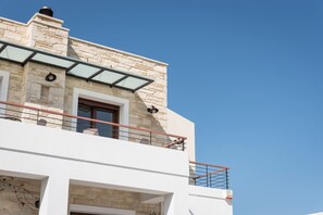 Ein modernes Gebäude mit Steinverkleidung, einem Glasbalkon und blauem Himmel.